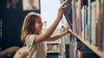 Une enfant choisit un livre sur une étagère de bibliothèque