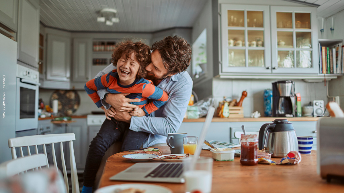 Un père joue et rit avec son enfant à la maison, symbole d’une parentalité positive alliant bienveillance, limites et complicité au quotidien.