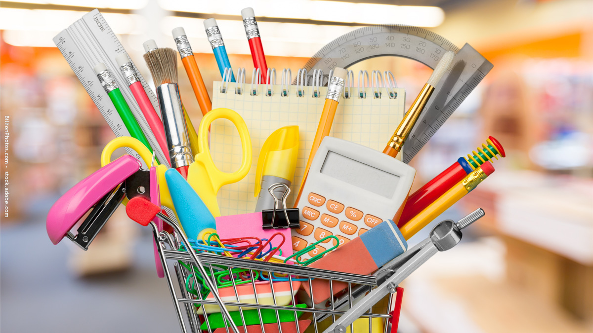 Fournitures scolaires dans un caddie : symbole de la préparation de la rentrée et de la charge mentale souvent assumée par les parents.
