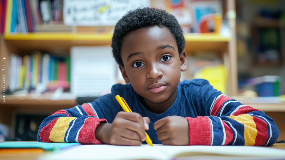 Enfant qui écrit sur un cahier avec un crayon