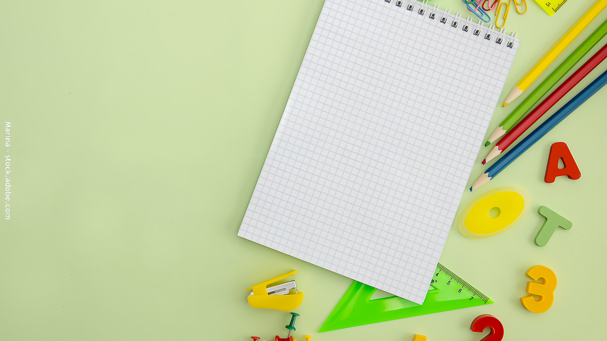 Fournitures scolaires colorées avec cahier à petits carreaux, crayons, règle et lettres magnétiques sur fond vert pastel.