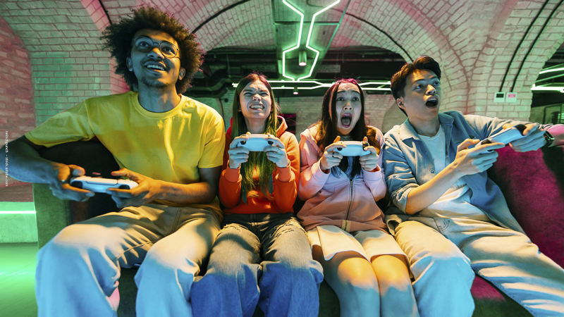 Adolescents jouant aux jeux vidéo dans une ambiance immersive, illustrant la question de l’impact des jeux vidéo sur le comportement.
