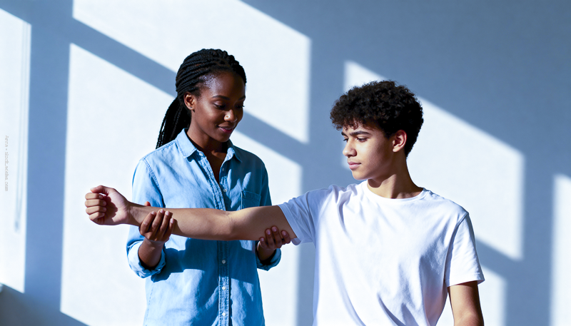 Adolescente tenant le bras d’un garçon, illustrant les douleurs physiques chez l’enfant et les questions autour des douleurs de croissance.