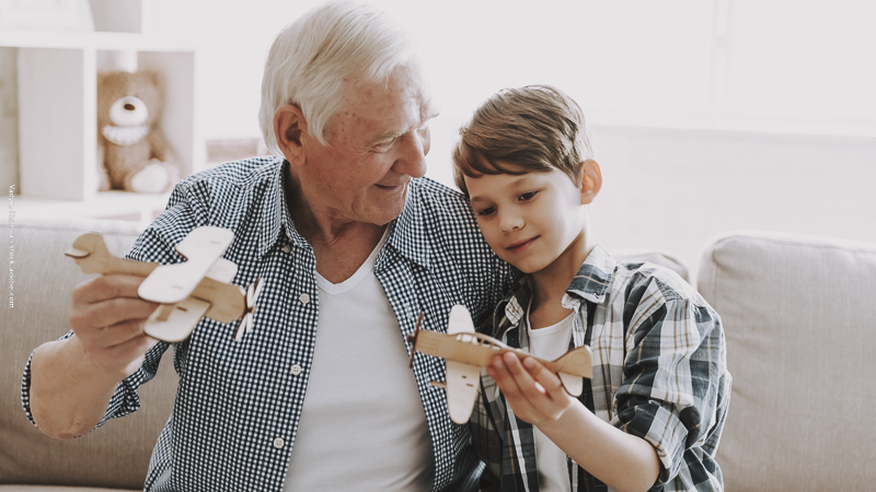 Grand-père et enfant jouant ensemble avec des jouets, illustrant la relation intergénérationnelle et le rôle des grands-parents.