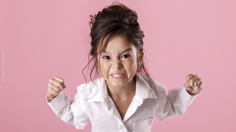 Petite fille en colère serrant les poings, illustrant une crise émotionnelle chez l’enfant et les difficultés parentales du quotidien.