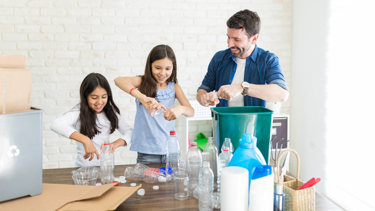 Famille qui trie les déchets plastiques à la maison. Un père et ses enfants apprennent le tri sélectif et les écogestes pour adopter un mode de vie plus écologique.
