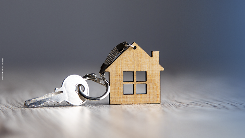 Clé et maison miniature en bois posées sur une table, illustrant la transmission d’un bien immobilier aux enfants.