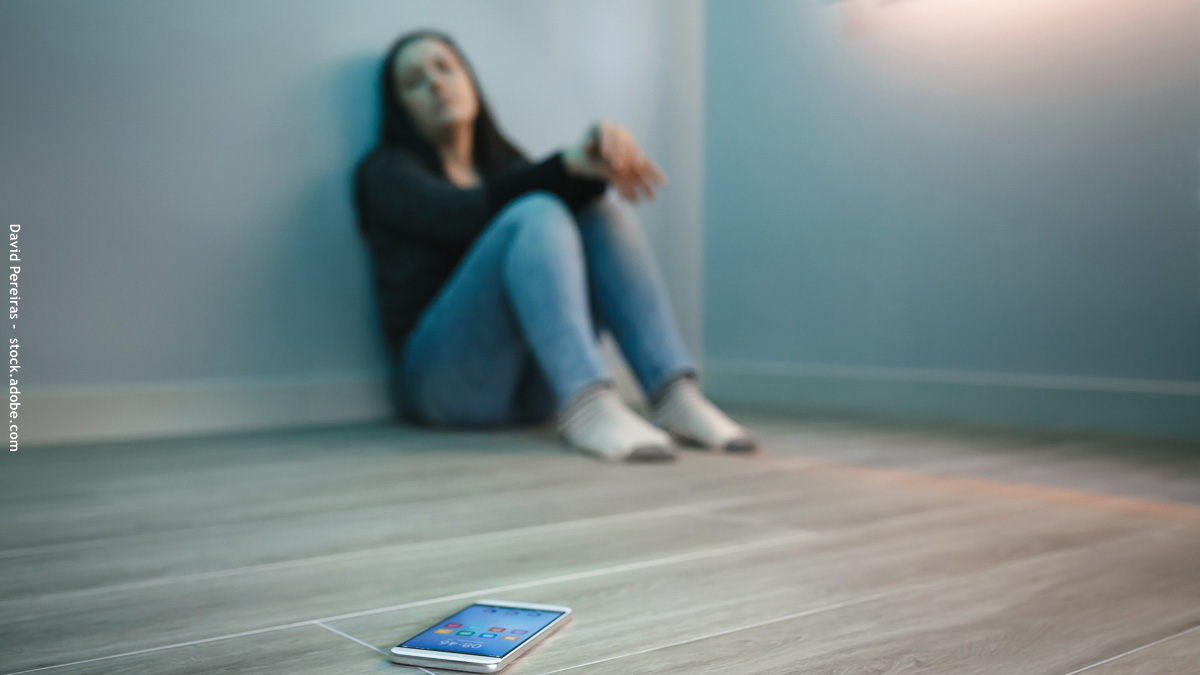 Adolescente qui regarde son smartphone posé loin d'elle sur le sol