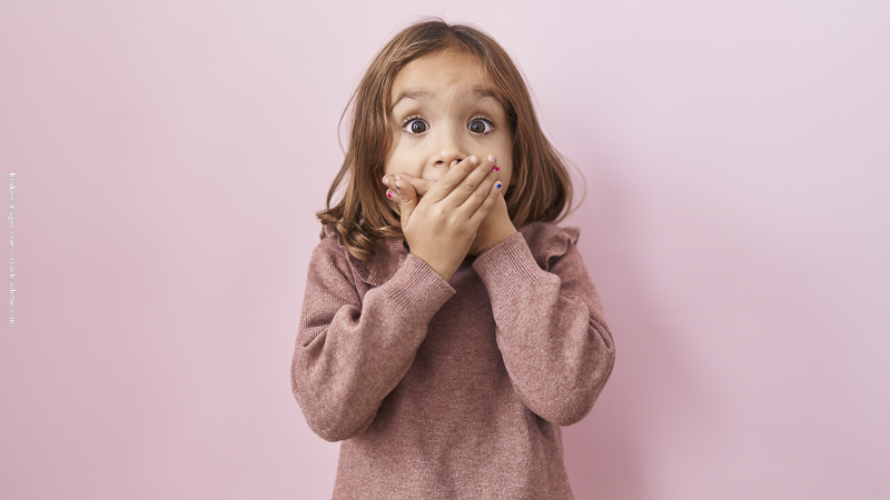 Jeune enfant bouche couverte, symbole du repli sur soi et du manque de communication dans la relation parent-enfant.