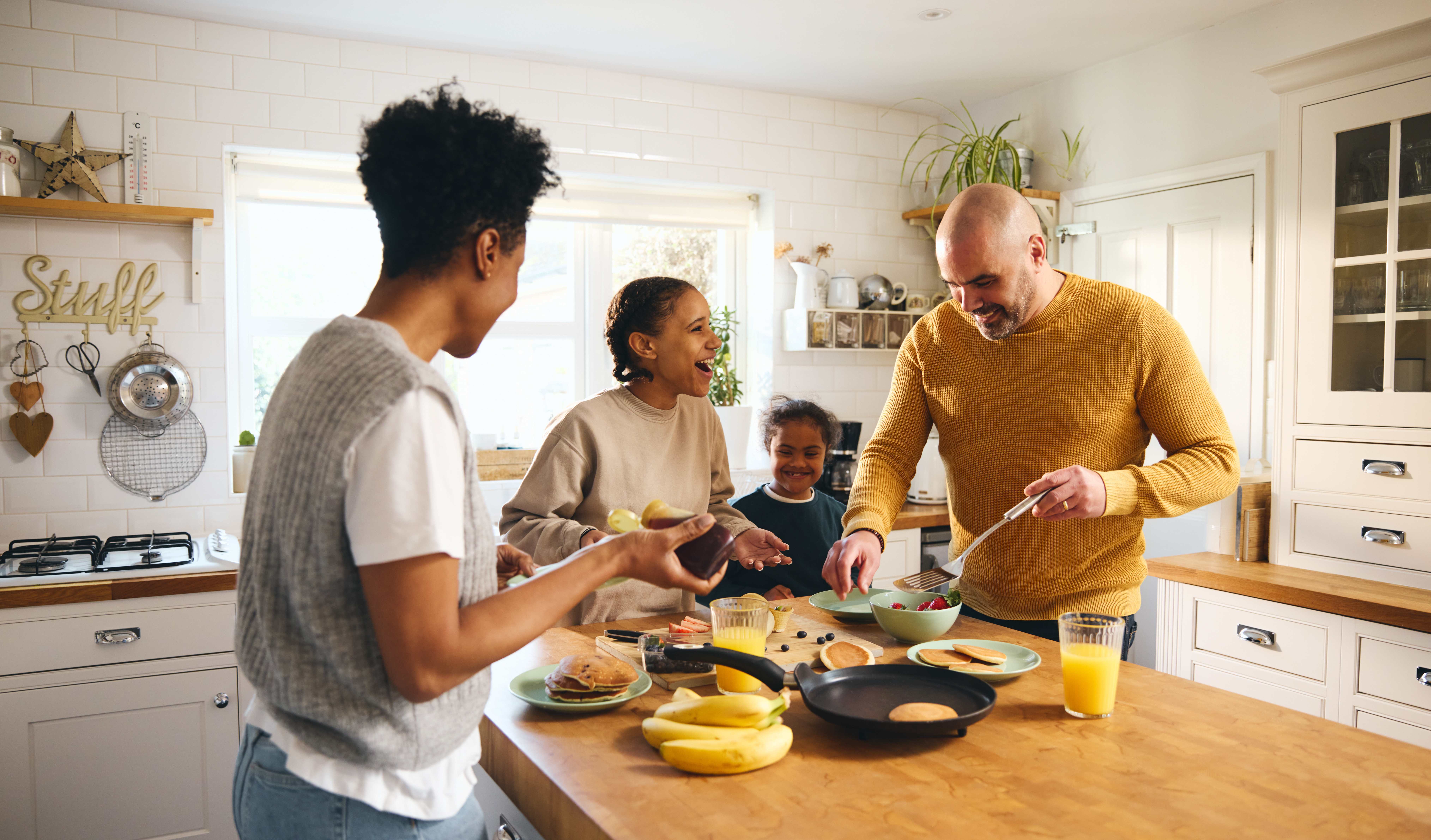 Parents et enfants réunis dans la cuisine autour d’un petit-déjeuner, symbole de la vie familiale et des relations entre frères et sœurs.