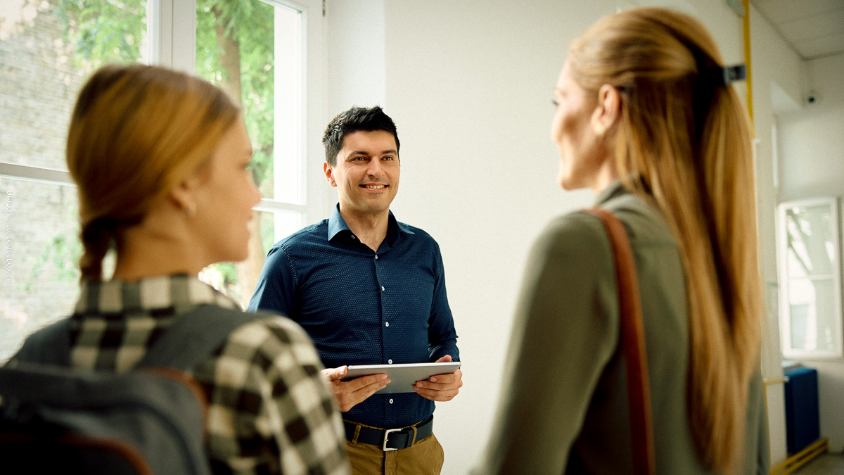 Un enseignant échange avec des parents à l’école, illustrant l’importance du dialogue et de la confiance pour accompagner la réussite des enfants.