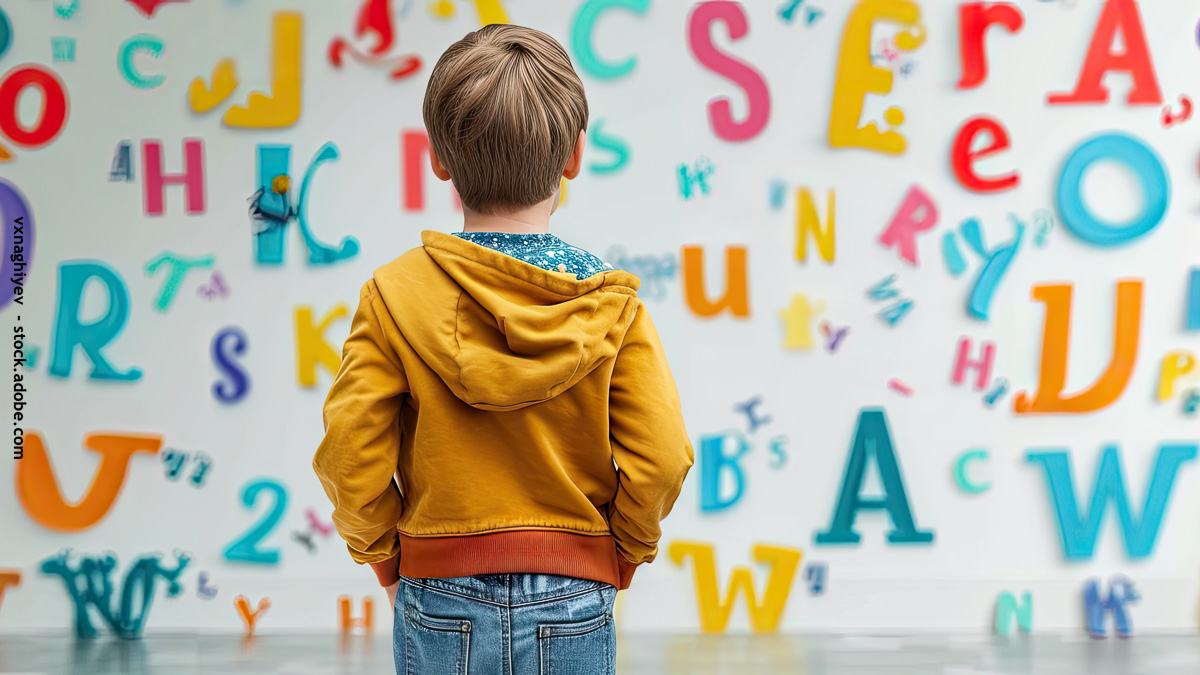 Enfant qui regarde un mur recouvert de lettre