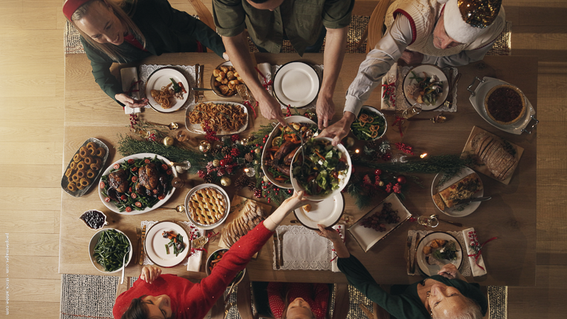 Grande tablée de Noël vue du dessus, convives partageant les plats — illustration d’un repas festif et de la gestion des restes sans gaspillage.
