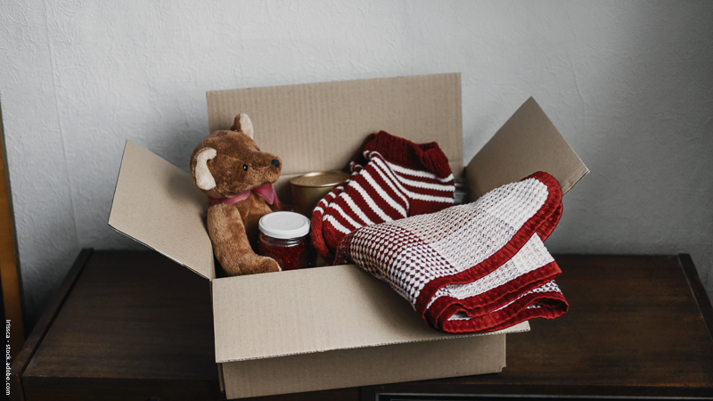 Carton rempli de jouets, peluche, vêtements et objets à donner — illustration d’une collecte solidaire de cadeaux de Noël pour enfants défavorisés.