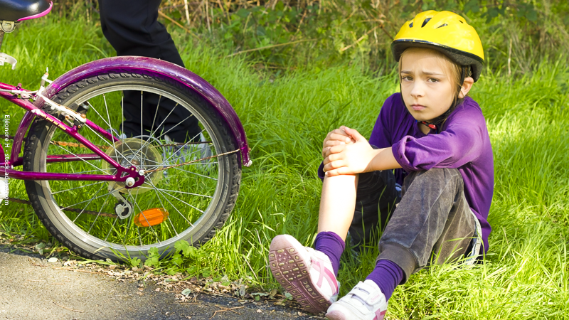 Enfant assis près de son vélo après une chute, illustration des petits bobos du quotidien chez l’enfant.